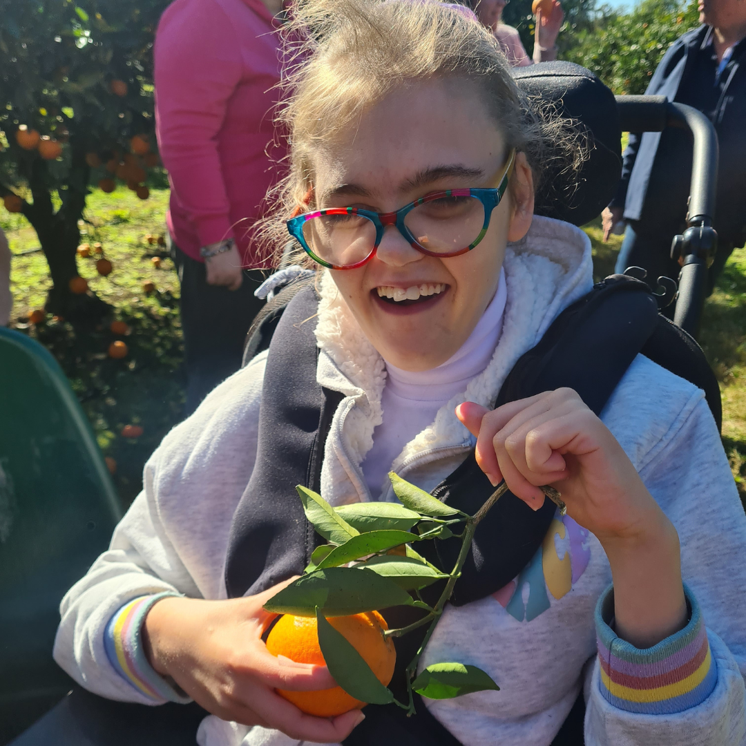 Coastlinker holding a freshly picked orange